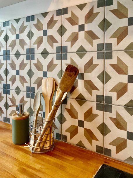 Mur de cuisine avec carreaux géométriques, ustensiles de cuisine sur un plan de travail en bois.