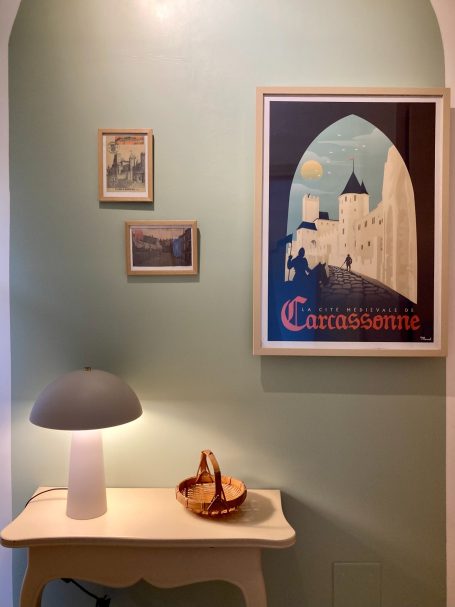 Intérieur avec des œuvres d'art, une lampe et un panier sur une table blanche.